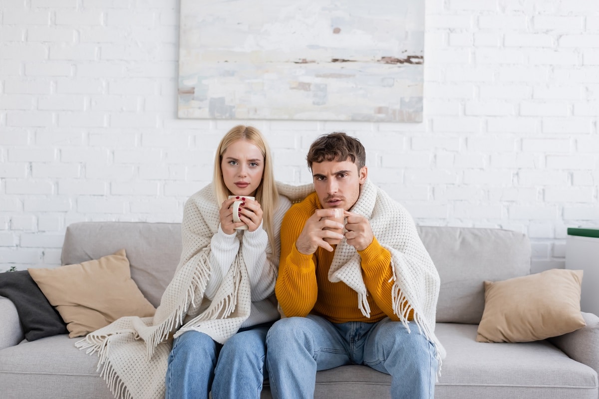 couple avec couverture assis sur le canapé